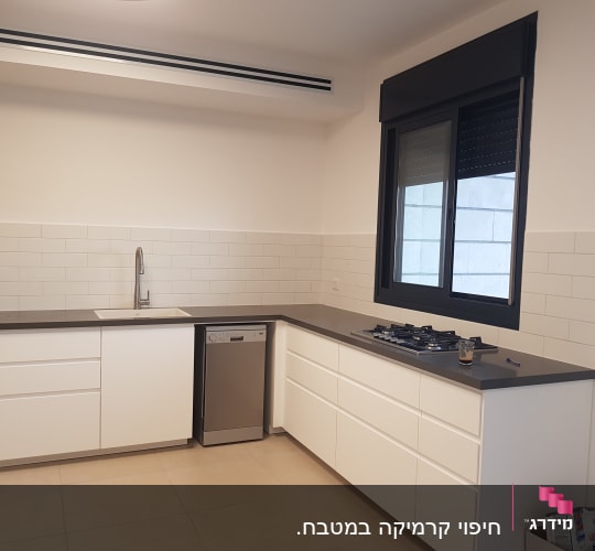 מטבח חדש עם ארונות לבנים ומשטח עבודה אפור